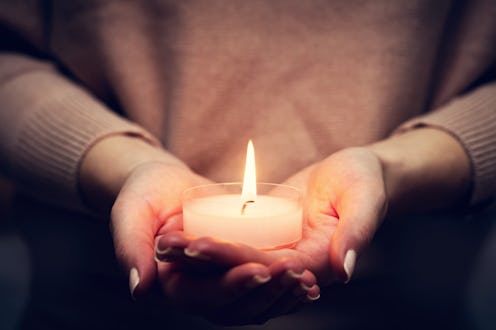 Candle light glowing in woman's hands. Praying, faith, religion concept.