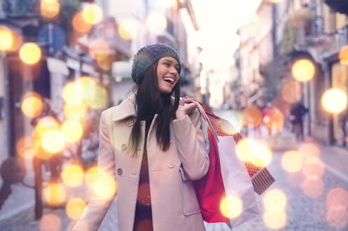 A beautiful girl smiles and is happy while shopping in the stores with sales at Christmas, around th...